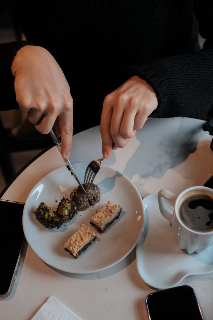 a person eating dessert on a plate with a cup of coffee